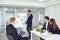 A group of young businessmen are listening to a coach`s speech at office.