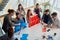 Group of young businesspeople playing, building card towers from paper, two teams, blue and red