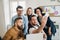 Group of young businesspeople with smartphone in office, taking selfie.