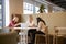 Group Of Young Businesswomen Sitting Around Table And Collaborating On Task Using Laptop