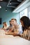 Group Of Young Candidates Sitting At Boardroom Table Making Notes At Presentation At Business Graduate Recruitment Assessment Day