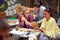 Group of young caucasian females reading together in outdoor cafe