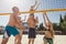 Group young caucasian friends playing volleyball on beach on summer vacation