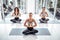 Group of young concentrated women with trainer meditating in yoga pose