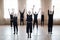 Group of young dancers in black activewear raising arms while training