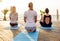 Group of young females practicing yoga on the seaside during the sunrise