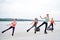 A group of young fit slim women in kangoo jumps, training in front of city lake in summer. Four sportswomen, wearing colorful