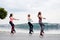 A group of young fit slim women in kangoo jumps, training in front of city lake in summer. Four sportswomen, wearing colorful