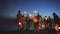 Group of young friends having a beach party. Friends dancing and celebrating with sparklers in twilight sunset