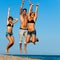 Group of young friends jumping on beach.