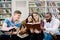 Group of young friends multiracial students, sitting in campus library, reading books while preparing for exams, test or