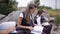 Group of young friends students wearing the same school uniform sitting and talking outdoors while reading a book on