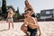 Group of young friends walking on the beach volleyball court.