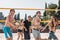 Group of young friends walking on the beach volleyball court.