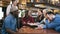 Group of young handsome friends making order from menu to the smiling waitress in the bar, pub.