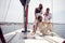 A group of young handsome models is joking while is posing for a photo on the deck of the yacht on the seaside. Summer, sea,