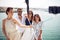 A group of young handsome models is posing for a photo on the deck of the yacht on the seaside. Summer, sea, vacation, friendship