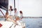 A group of young handsome models is relaxing with a coffee on the deck of the yacht and chatting while riding through the dock on