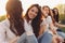 Group of young happy girls friends enjoy life on summer city street, sunset background