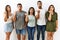 Group of young hispanic friends standing together over isolated background surprised pointing with hand finger to the side, open