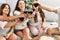 Group of young hispanic women celebrating pajamas party toasting with red wine at home