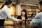 Group of young interracial couple people sitting indoor restaurant eating food together for lunch. Women customer receiving food