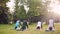 Group of young ladies is practising yoga outdoors in park on autumn day, flexible girls are exercising on mats. People