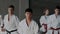 Group of young male and female athletes practice martial arts in taekwondo school. White kimono, focused mind and faces