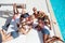 Group of young multiethnic friends rest at poolside during vacation