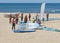 Group of young people on the beach in suits for windsurfing