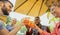 Group of young people having fun outside in a bar with drinks in summer - Friends cheering with coktail and smiling laughing with