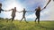 A group of young people lead a round dance holding hands on a summer day. Unity concept.