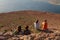 A group of young people look at a nearby island in the ocean, sitting near a cliff