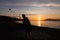 Group of young people playing beach volleyball silhouetted against the sunset at Kits Beach in Vancouver, BC.