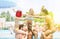 Group of young people playing in swimming pool party outdoor - Multi ethnic cheerful friends enjoying aqua park in summer time -