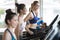 group of young people running on treadmills in sport gym .fitness woman runner on running machine with trainer man in morning time