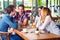 Group of young people sitting at a cafe, talking and enjoying