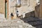 A group of young people stand near a very old stray dog in a residential area of the ancient historic center of Matera, Italy
