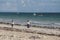 Group of young people walking along the beach on sunset background. Students and there parents going home.