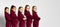 Group of young smiling girls gymnasts in dark red velvet sport costumes standing and posing