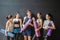 Group of young sporty people with fitness yoga exercise mats standing beside black wall.Students taking a rest from fitness