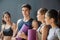 Group of young sporty people with fitness yoga exercise mats standing beside black wall.Students taking a rest from fitness