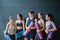 Group of young sporty people with fitness yoga exercise mats standing beside black wall.Students taking a rest from fitness