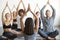 Group of young sporty people sitting in Sukhasana pose