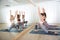 Group of young sporty women in yoga studio, practicing yoga pose in front of the mirror. Healthy active lifestyle