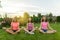 Group of young teenage girls practice yoga, meditate, sit in a lotus position on the grass near the house
