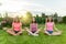 Group of young teenage girls practice yoga, meditate, sit in a lotus position on the grass near the house