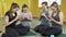 Group of young women actively using phones. Four girl sitting on the mat totally focused on their smartphones in studio.