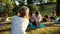 Group of young women stretching her legs on yoga mat in park on summer