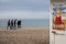 Group of youths walking along brighton beach with saucy seaside image